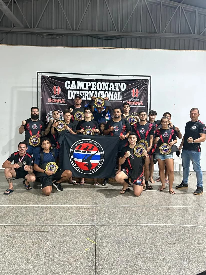 Delegação da Equipe FFT com as medalhas e a bandeira da equipe sob o painel do campeonato internacional