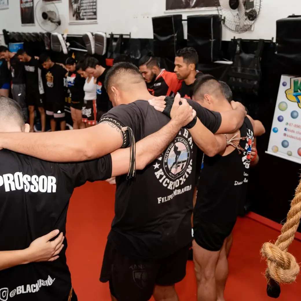 Alunos e professores da Equipe FFT abraçados em roda antes do início do treino