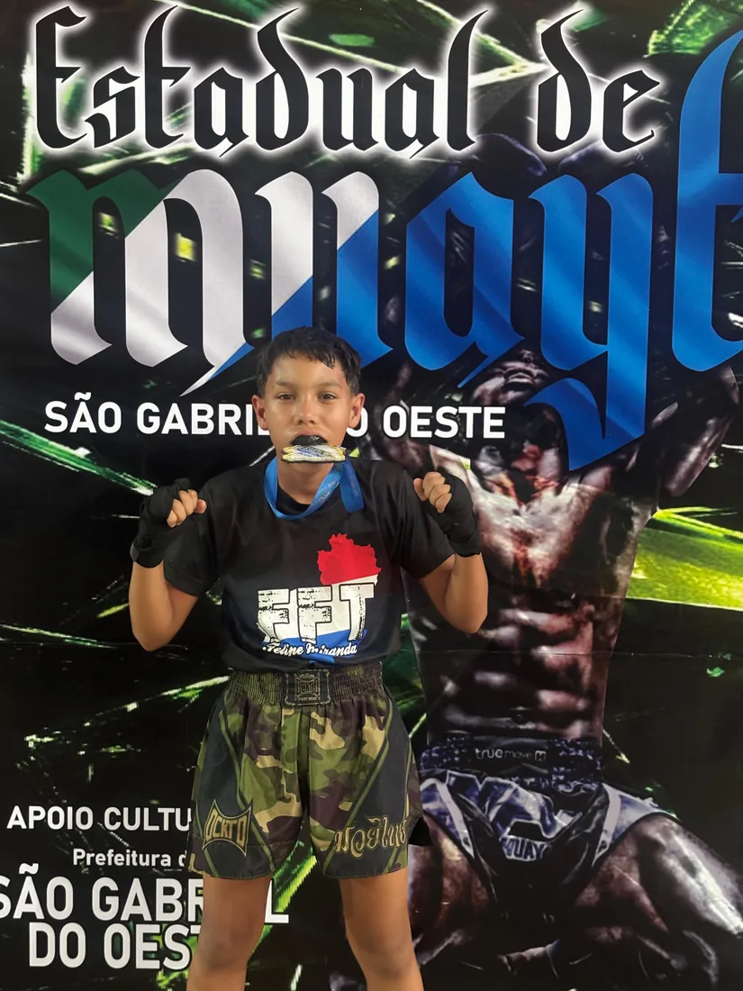 Jovem atleta da Equipe FFT mordendo a medalha de ouro no Estadual de Muay Thai de São Gabriel do Oeste