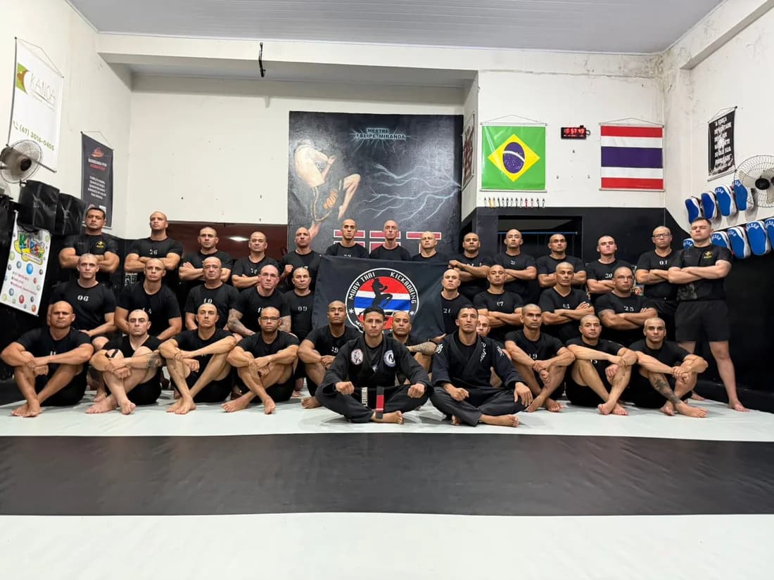 Equipe FFT reunida na academia de Dourados para foto oficial, com as bandeiras do Brasil e da Tailândia ao fundo