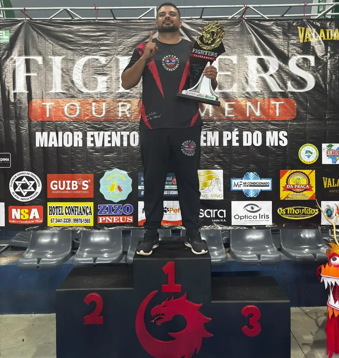 Mestre Felipe Miranda no primeiro lugar do pódio do Fighters Tournament, segurando o troféu da competição